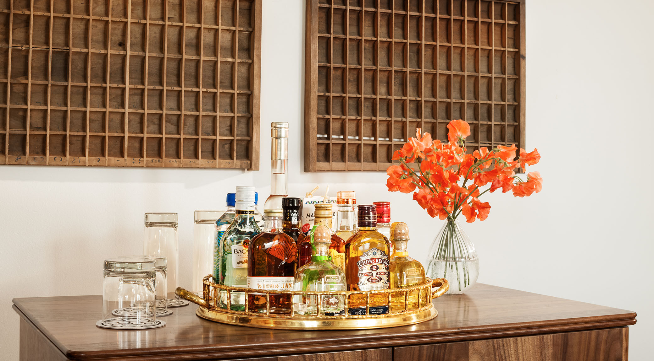 table top bar with several alcoholic beverages and a vase with several orange flowers